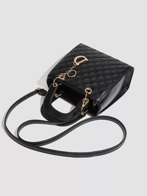 Black quilted mini top-handle tote bag with gold hardware and a detachable strap.