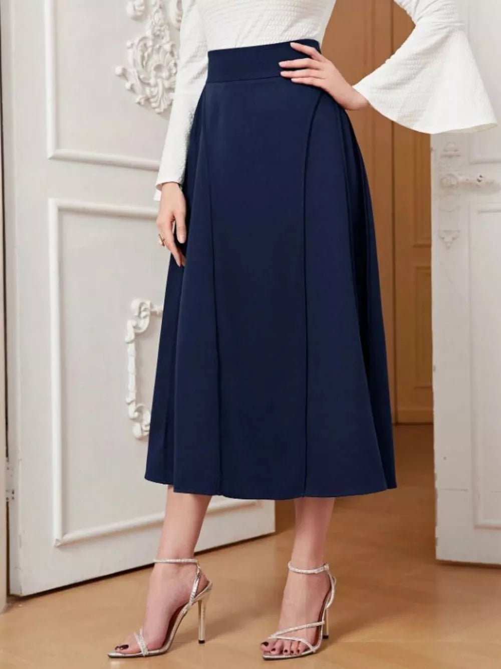 Elegant navy high-waisted midi skirt with a flared A-line cut, styled with a white bell-sleeve top.