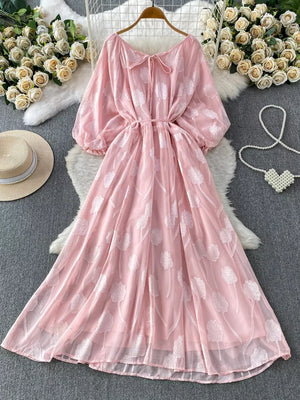 Pink chiffon maxi dress with floral embroidery, puff sleeves, and a tie neck.