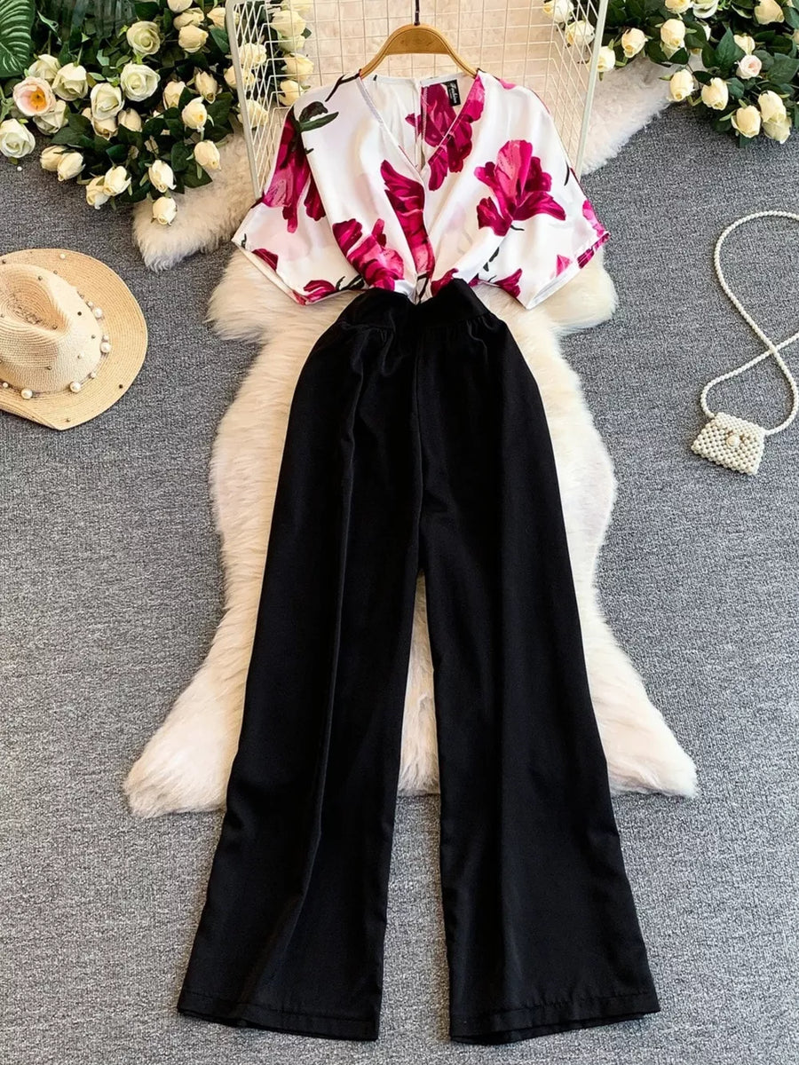 Black wide-leg maternity romper with abstract floral print V-neck top and pockets.