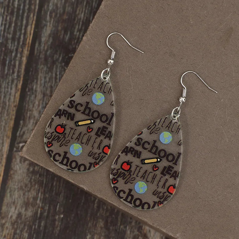 Schoolhouse graphic teardrop earrings in transparent acrylic with school-themed icons and text.