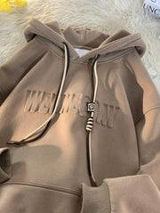 Tan cotton blend hoodie with embossed text and drawstring detail.