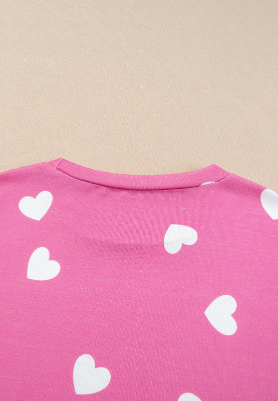 Hot pink long sleeve top with white hearts, round neck.