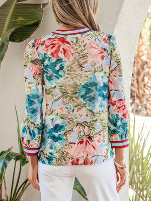 Women's V-neck blouse with a vibrant floral print, striped cuffs, and puff sleeves.