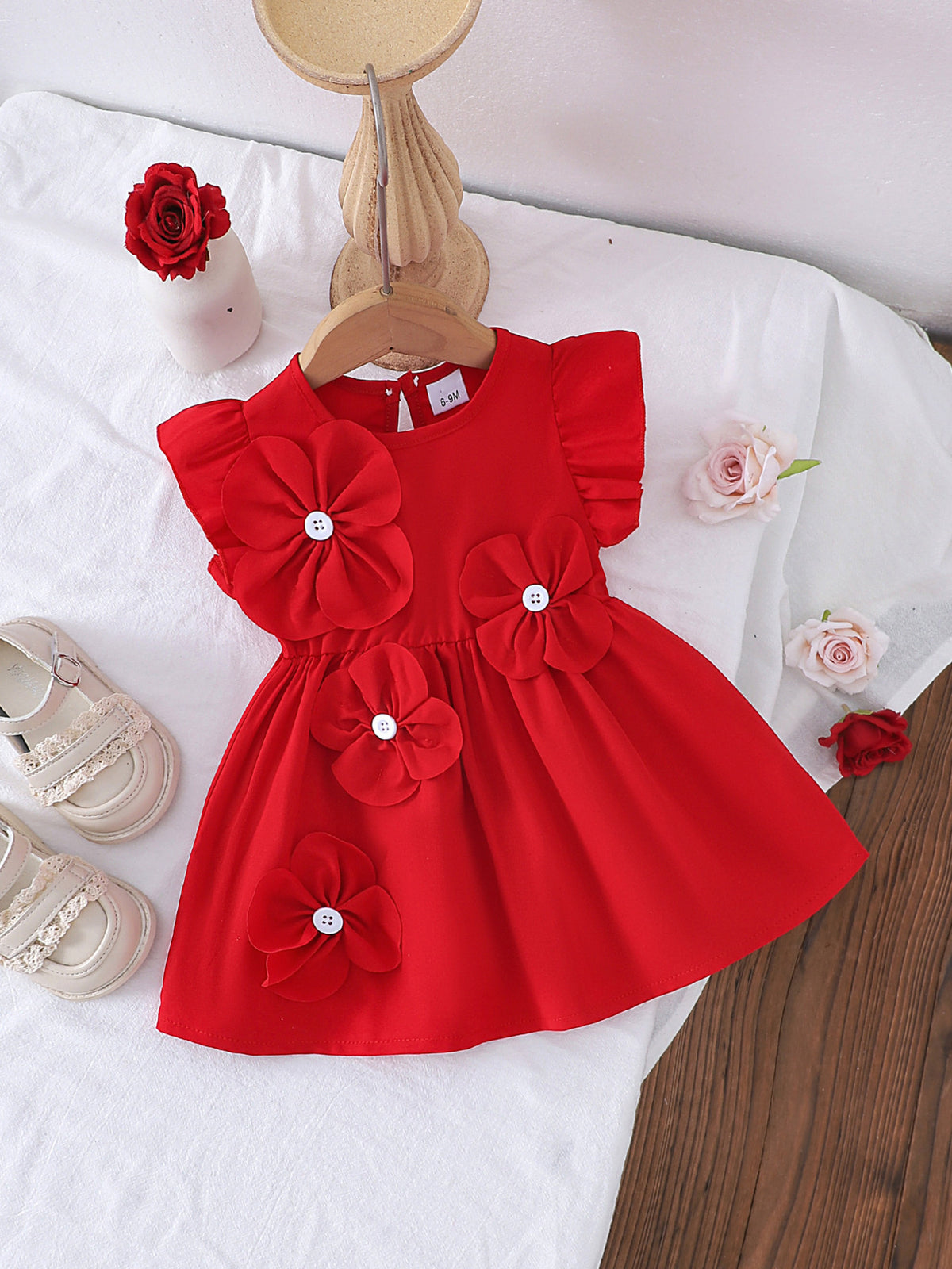 Red cotton baby dress with ruffle sleeves and large flower appliqués.
