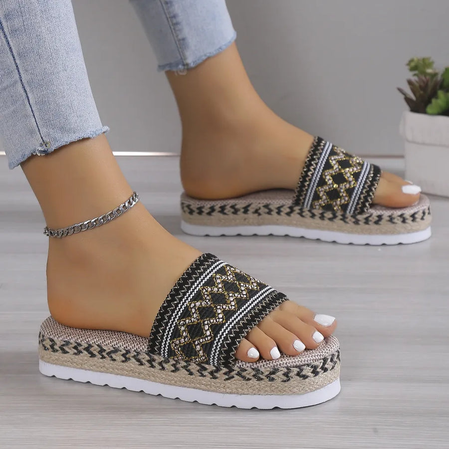 Embroidered platform espadrille slides in black with geometric pattern and rope detail.