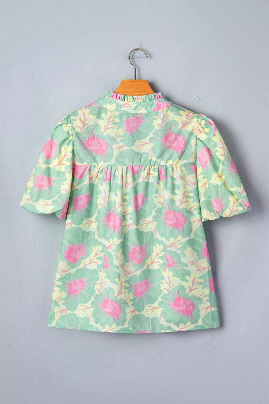 Pastel floral print polyester blouse with ruffled mock neck and puff sleeves.