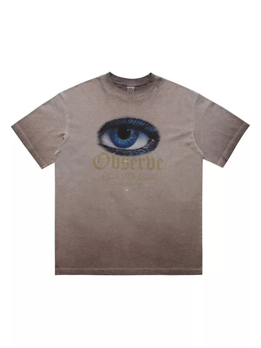T-shirt in taupe with a graphic of a blue eye and gold text that says Observe.