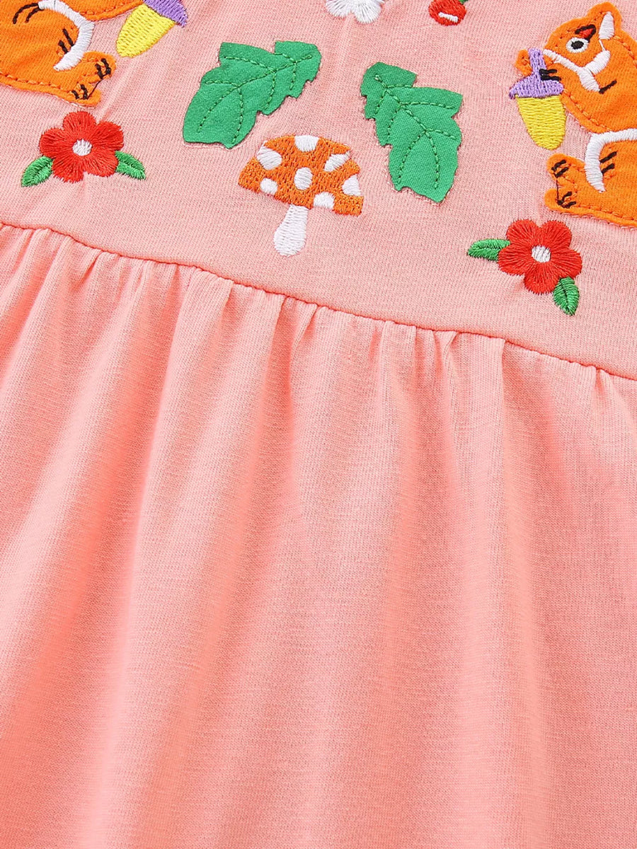 Peach cotton toddler dress with playful animal, mushroom, and flower embroidery.