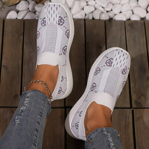 White breathable mesh slip-on sneakers with a geometric pattern and white soles.