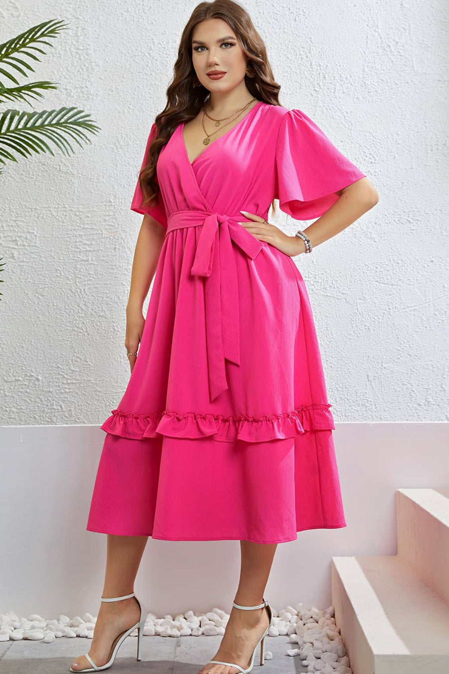Hot pink wrap-front midi dress with flutter sleeves, belted waist, and tiered ruffled hem.