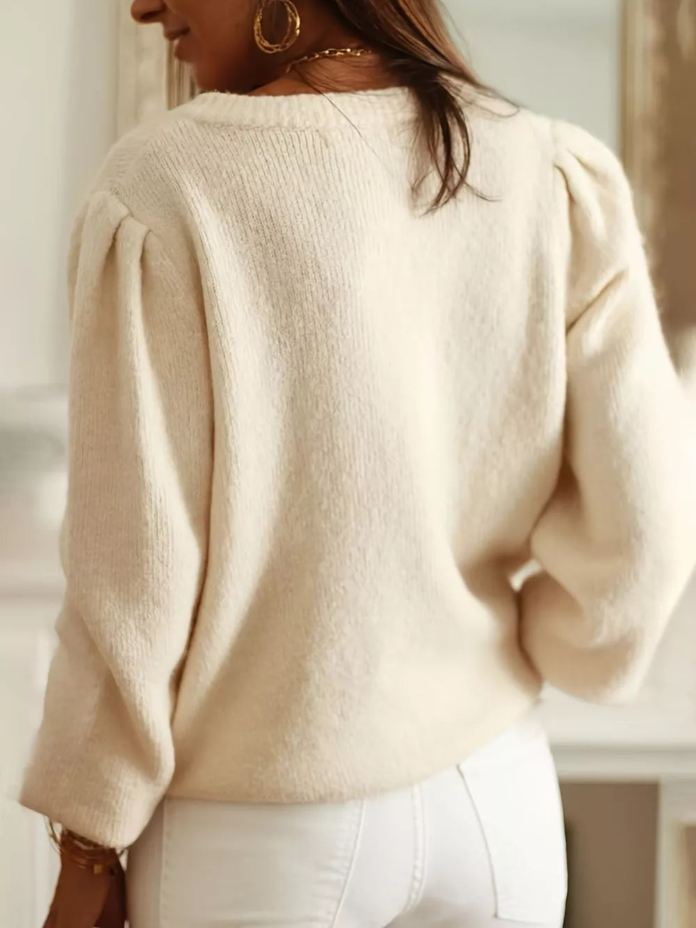 Cream knit cardigan with puff sleeves and eyelet detail.