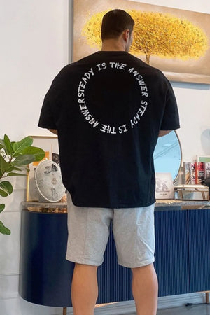Black oversized t-shirt with white circular text graphic on back