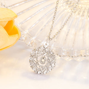 Silver-plated sterling pendant necklace with a woven circular design and small crystal accent.