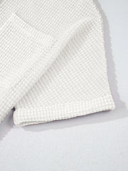 White waffle knit button-up shirt detail showing texture and rolled sleeve cuff.