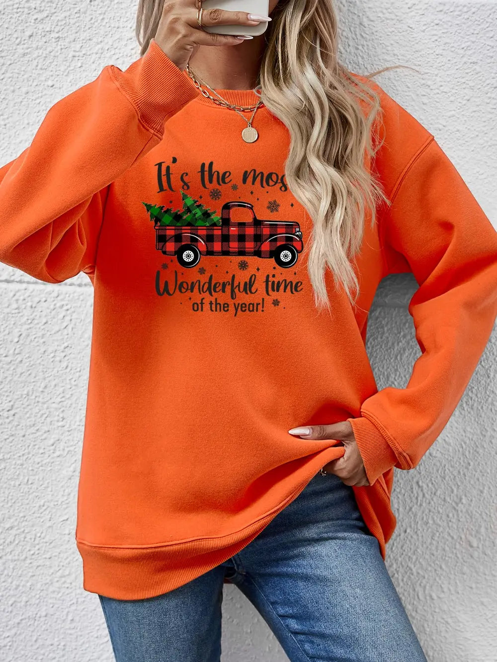 Orange sweatshirt with Christmas truck graphic and text.
