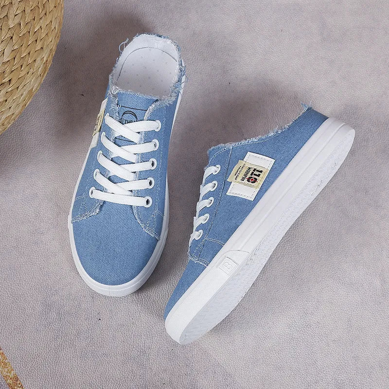 Light blue denim mule sneakers with raw edges and white laces.
