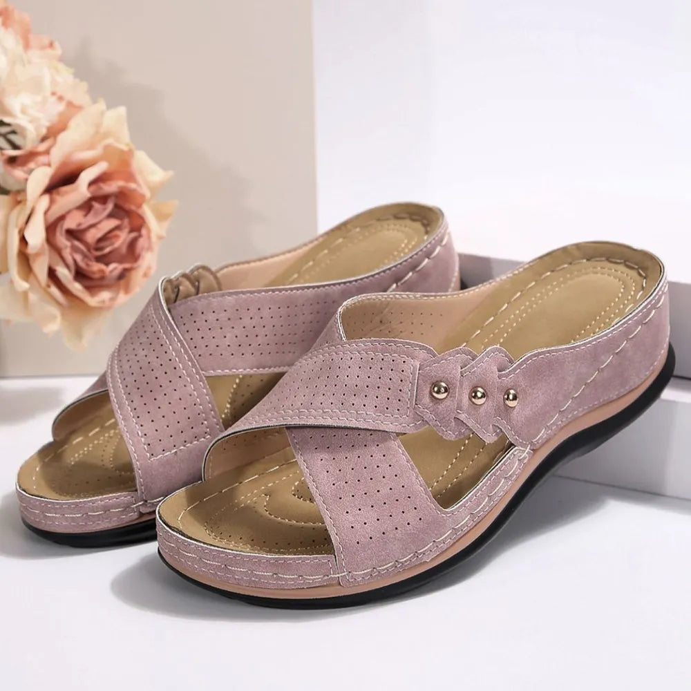 Perforated cross-strap comfort sandals in pink with decorative studs and cushioned footbed.