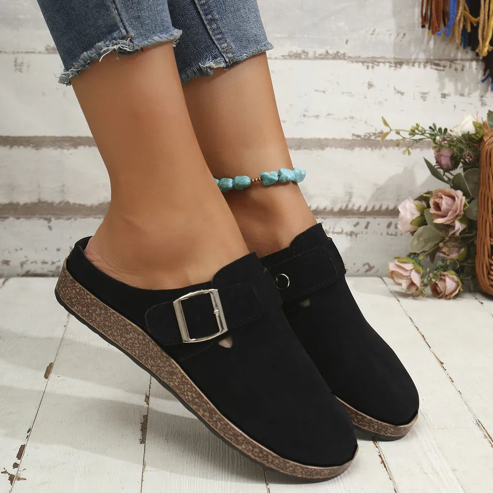 Black suede mule flats with buckle detail and cork sole.