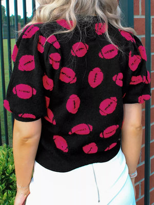 Black short-sleeve knit sweater with all-over pink football print and puff sleeves.