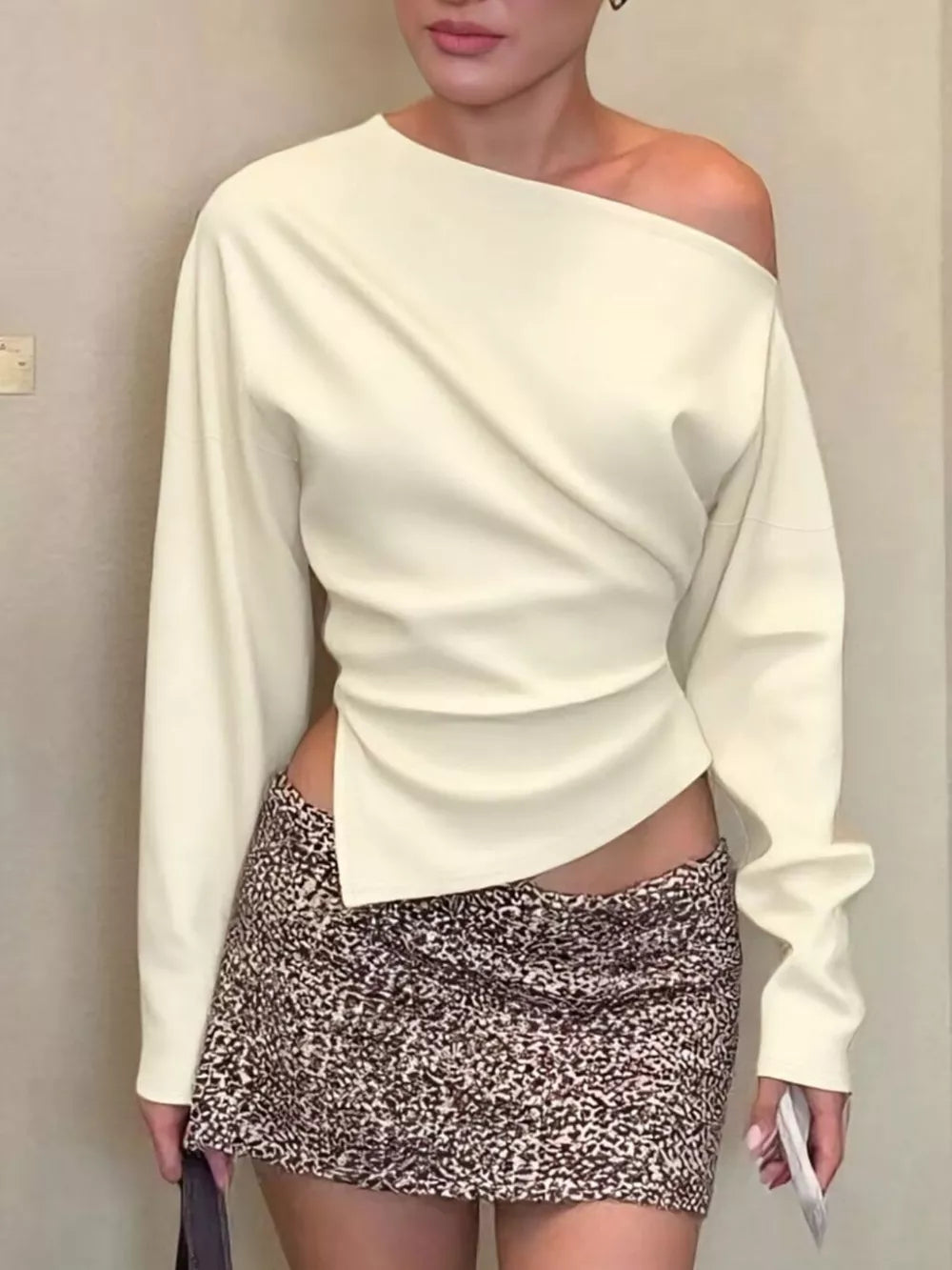 Apricot draped asymmetrical off-shoulder t-shirt with long sleeves.