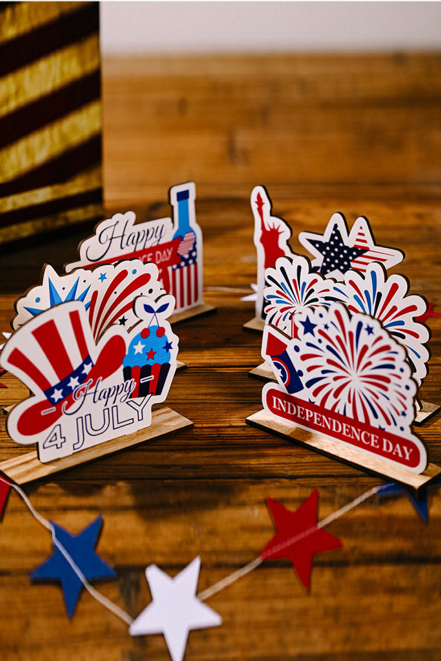 Patriotic Americana wooden tabletop decor with USA flag motifs, fireworks, Statue of Liberty, and holiday messages.