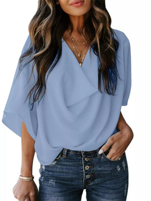 Sky blue flowy half sleeve blouse with draped neckline, styled with jeans.