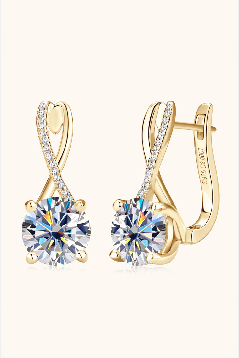Gold crossover moissanite huggie earrings with diamond accents and a large center stone.