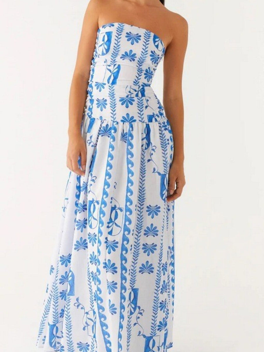 Strapless maxi dress in white with blue floral and scroll pattern, ruched bodice, flowing skirt.