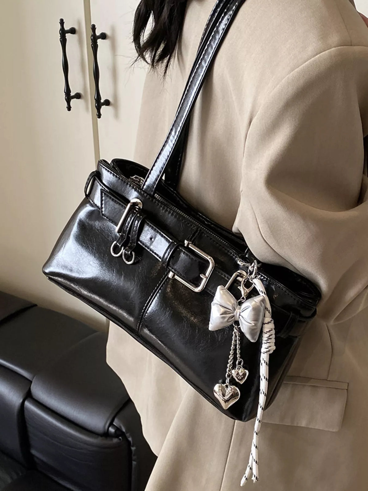 Black shoulder bag with buckle detail and heart and bow charms.