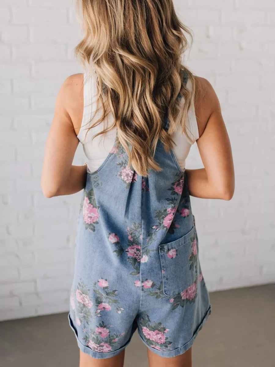 Denim overalls shorts with pink floral print and cuffed hems.