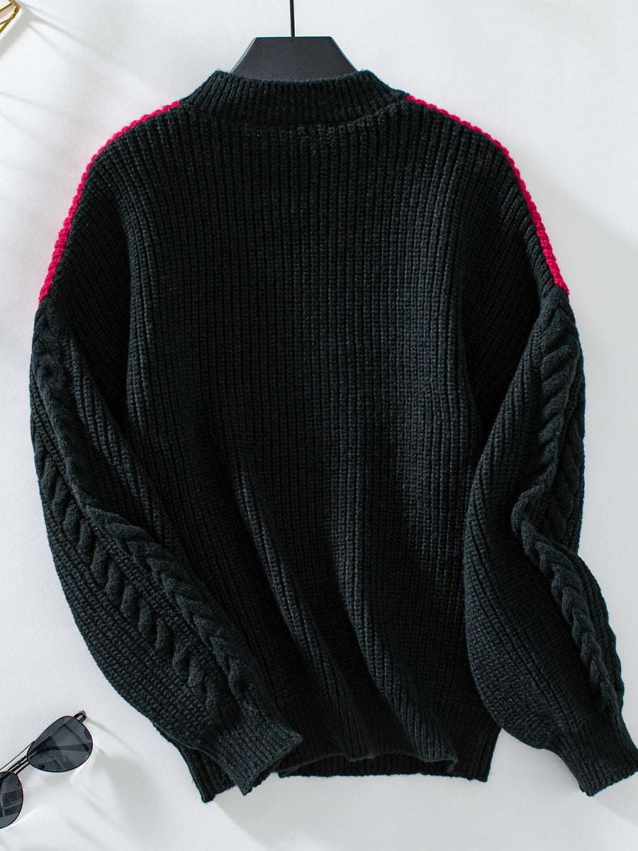 Black cable knit sweater with contrast pink shoulder detail and mock neck.