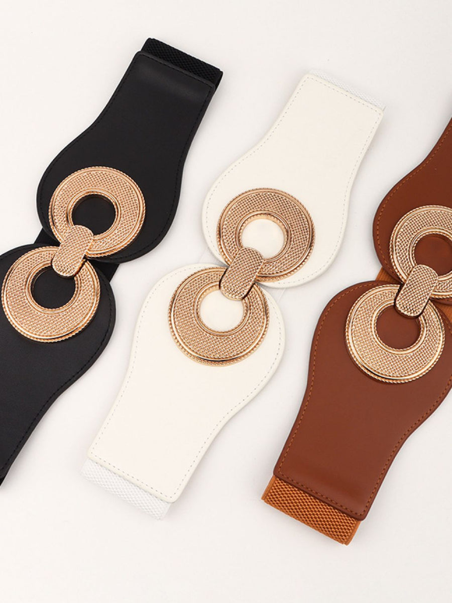 Black, white, and caramel elastic belts with sculpted metalwork circular buckle detail