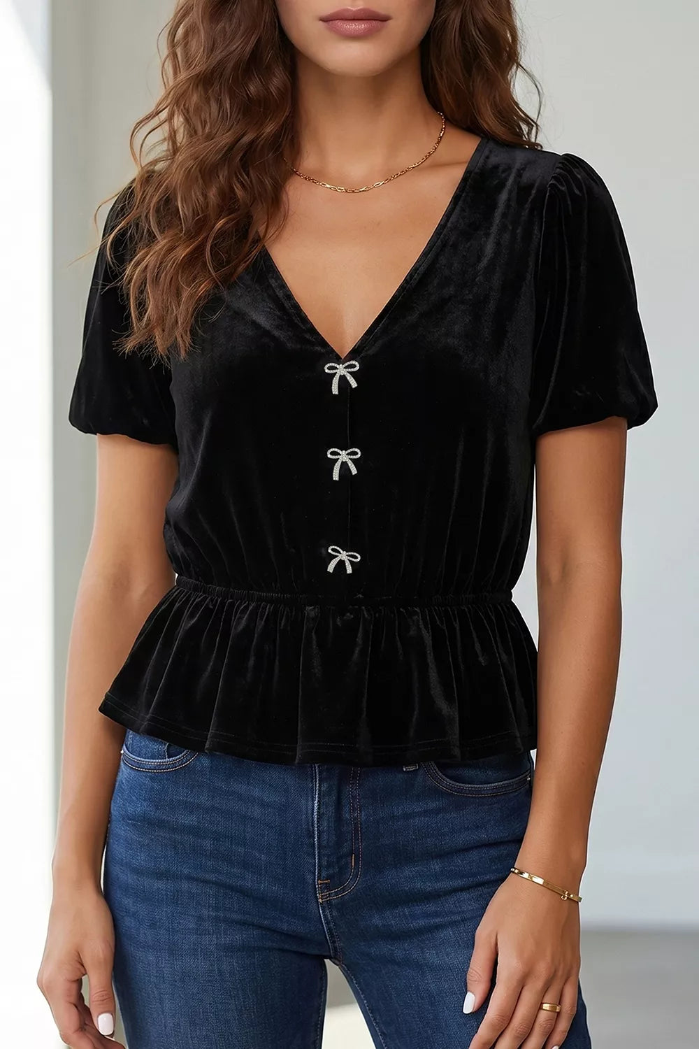 Black velvet peplum shirt with V-neck, short puff sleeves, and bow button front.