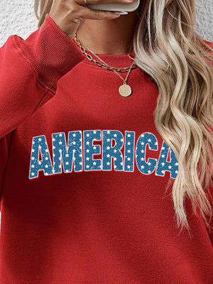 Red crewneck sweatshirt with AMERICA graphic in distressed blue stars and stripes.