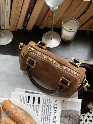 Vintage barrel crossbody bag in coffee brown suede with gold hardware and top handles.