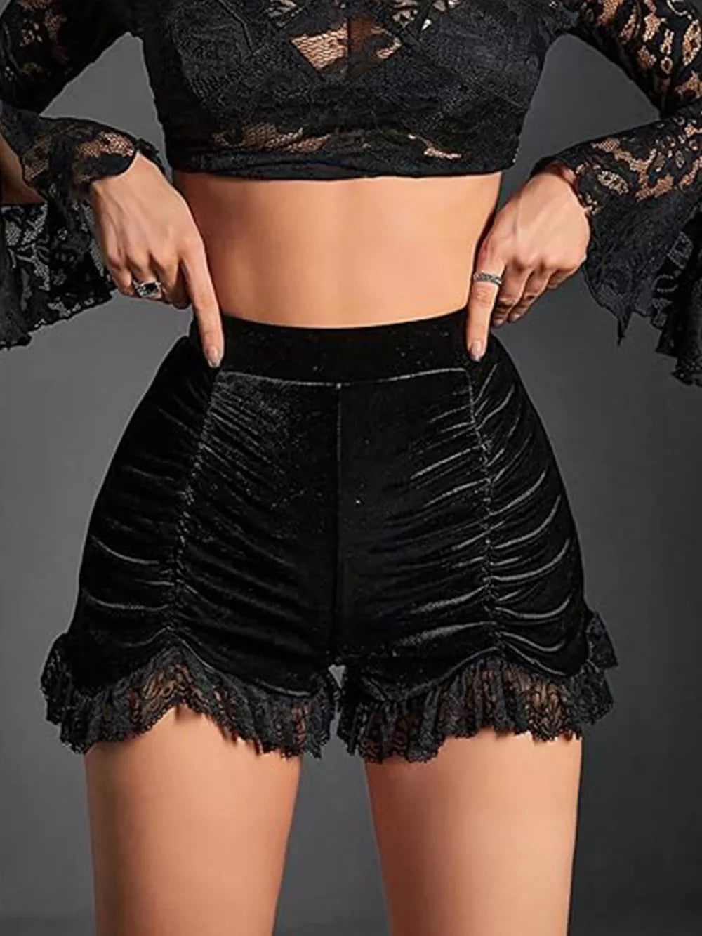 Black velvet high-waisted shorts with ruched detailing and lace trim.