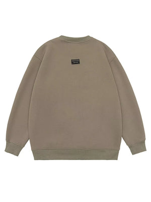 Oversized khaki cotton crew-neck sweatshirt with a small black logo patch on the back.