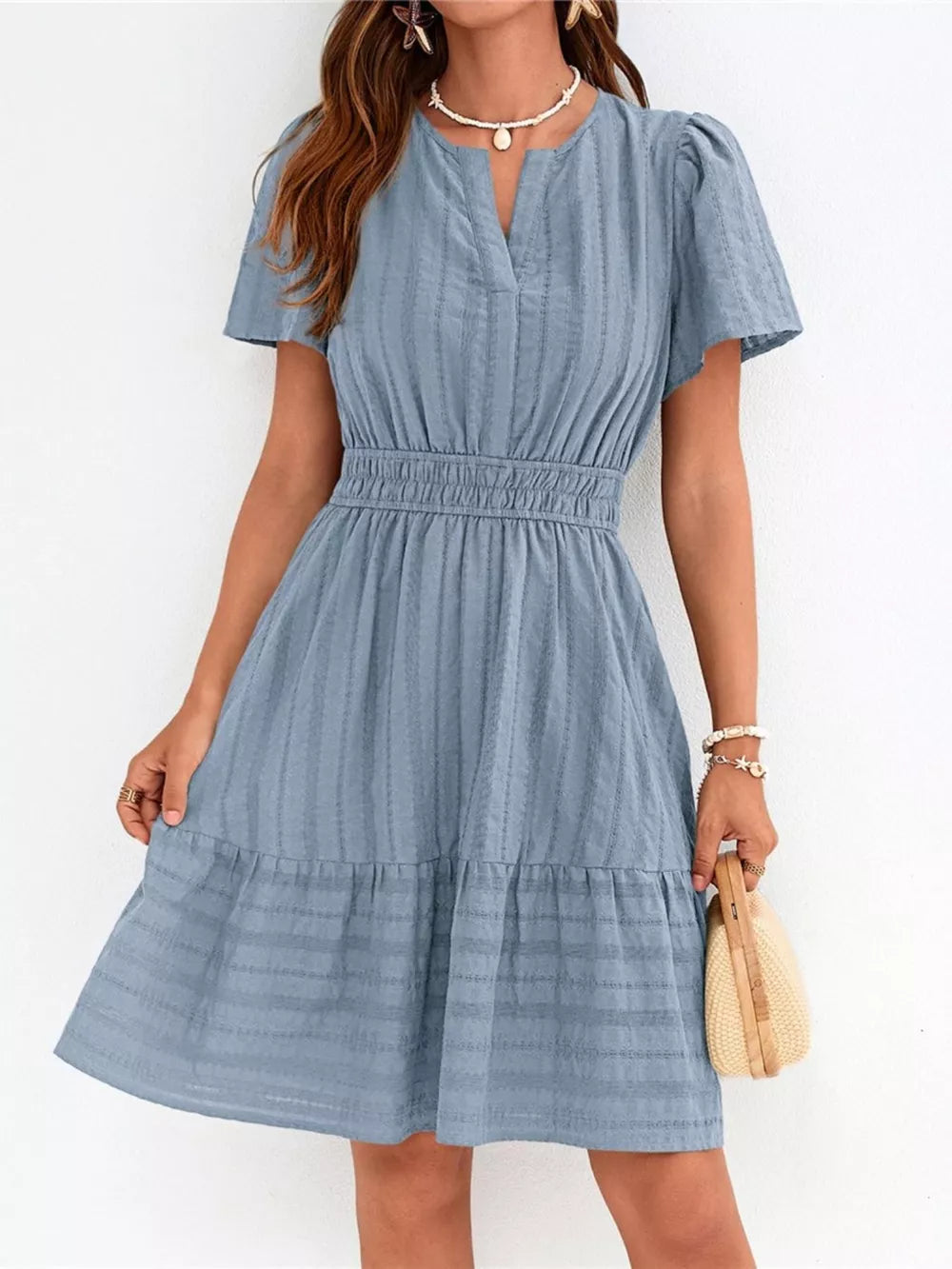 Light blue textured V-neck tiered dress with smocked waist and short sleeves.