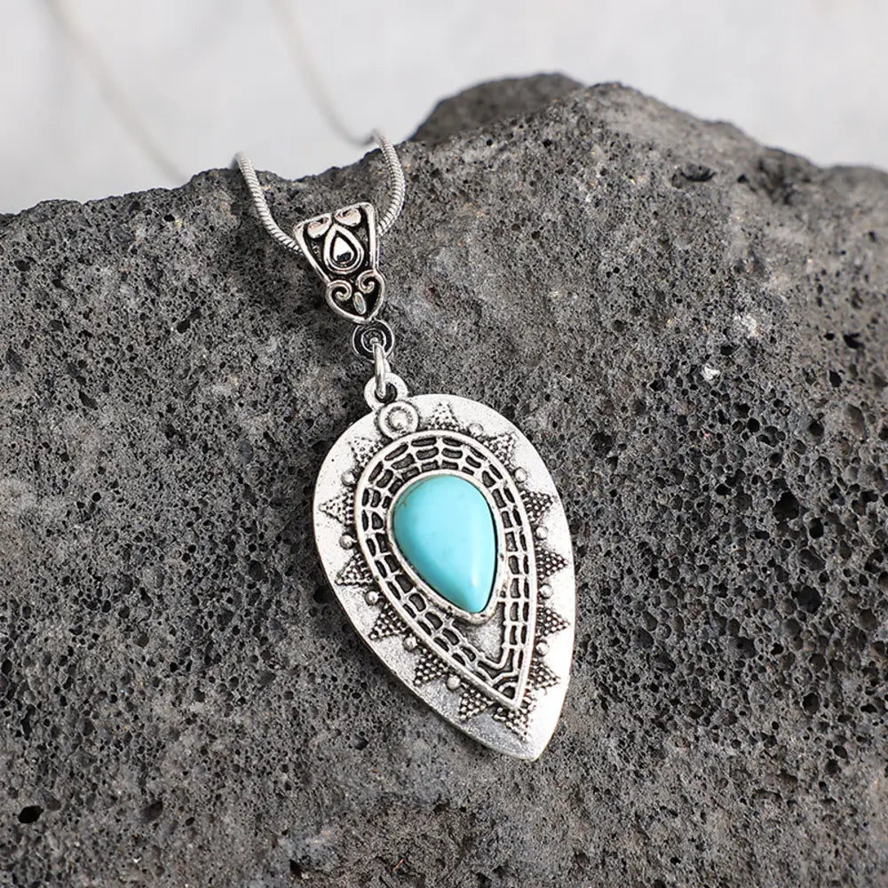 Silver teardrop pendant necklace with turquoise inlay and boho detailing.
