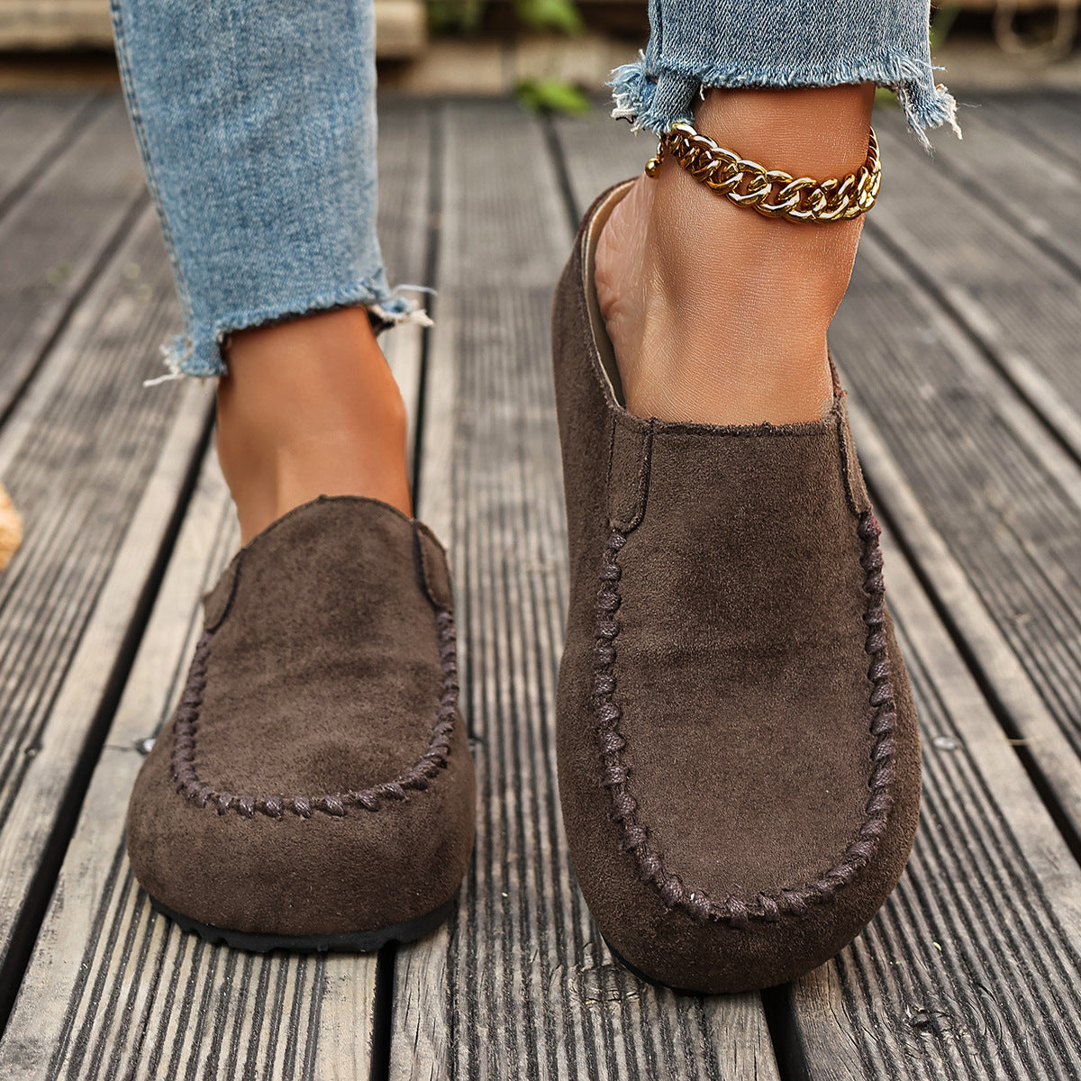 Brown suede slip-on flats with round toe and decorative stitching detail.