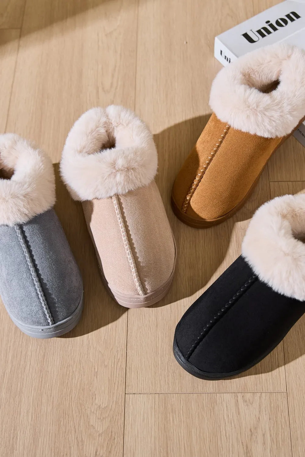 Suede house slippers with plush shearling trim in gray, beige, caramel, and black.