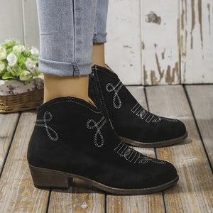 Black suede ankle boots with white western embroidery and side zipper.