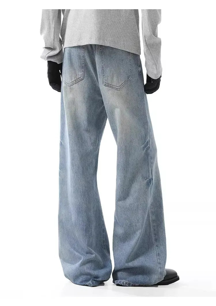 Men's light wash wide-leg jeans with button closure and distressed details.