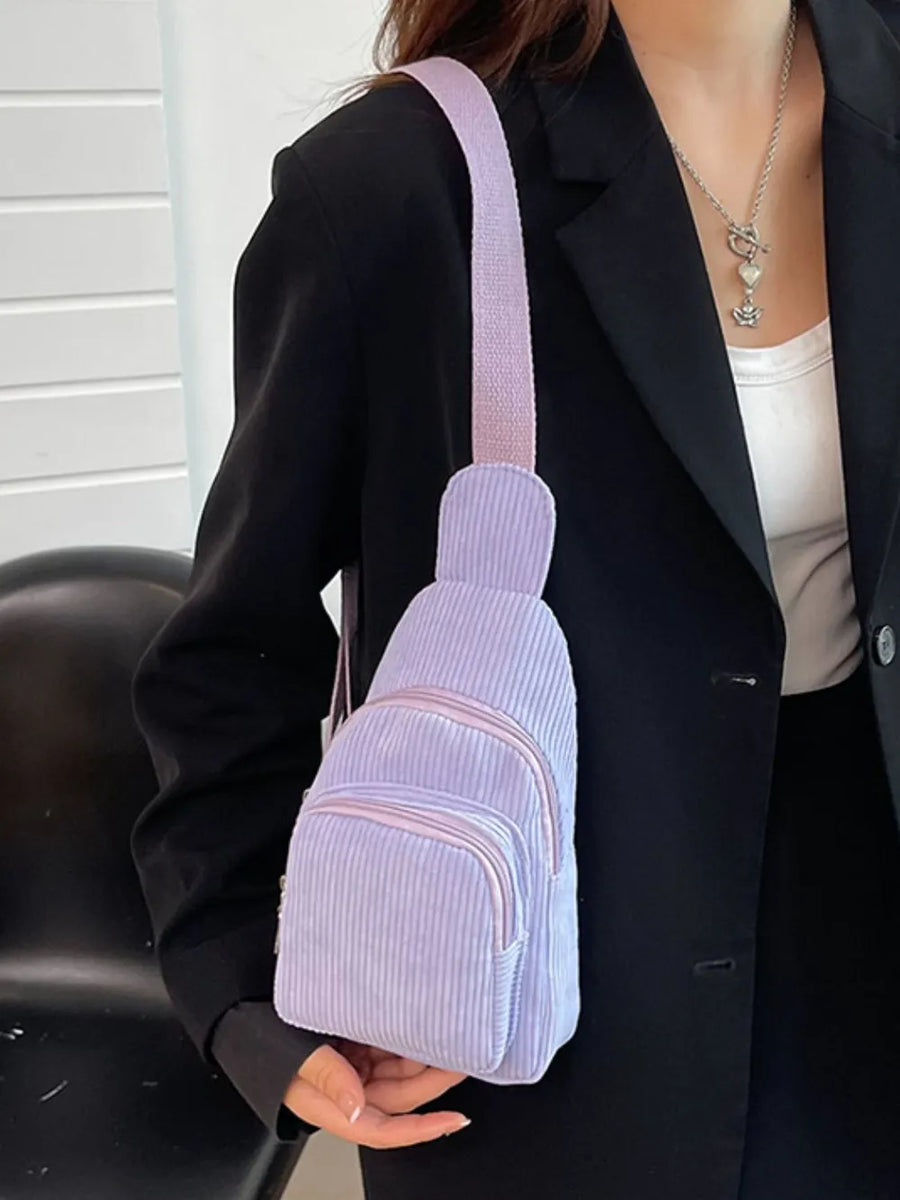 Lavender corduroy sling bag with zip pockets and adjustable strap.