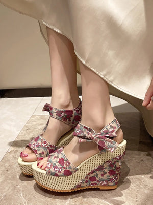 Floral bow wedge sandals with a woven wedge and ankle strap detail.