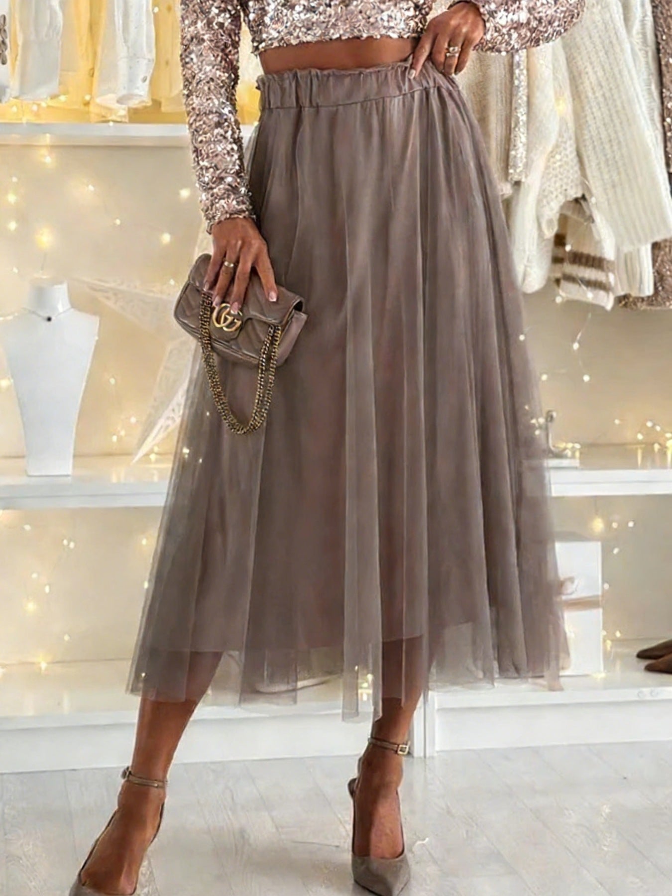 Sheer mesh A-line midi skirt in taupe with elastic waistband, styled with a sequin top and heels.