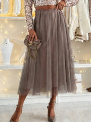 Sheer mesh A-line midi skirt in taupe with elastic waistband, styled with a sequin top and heels.