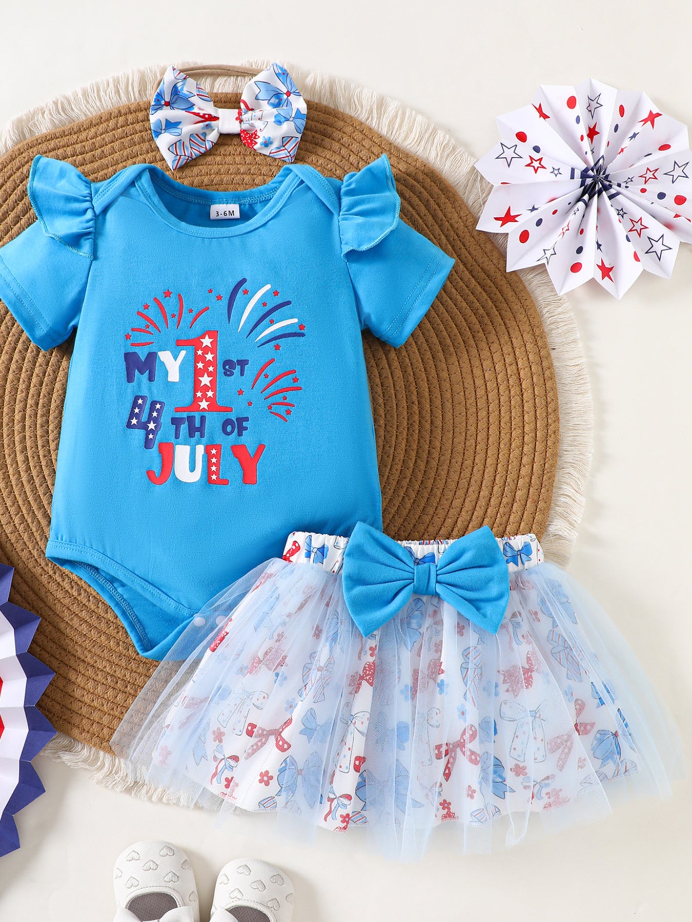 Blue cotton baby outfit with ruffled sleeves and "My 1st 4th of July" graphic, paired with a bow-adorned tutu skirt.