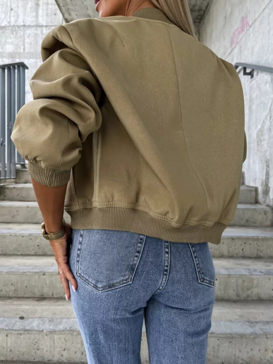 Olive bomber jacket with sculpted sleeves and ribbed cuffs, styled with jeans.